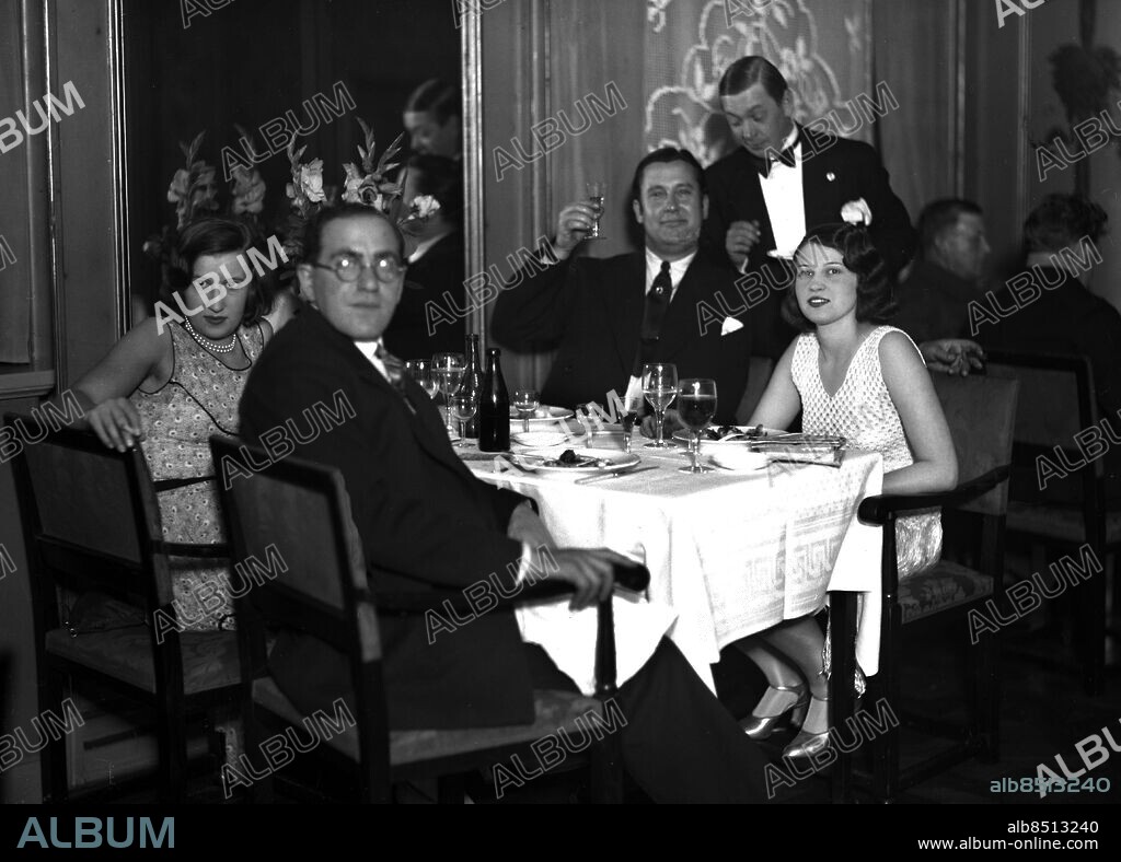 ARKIV 1930 (Omkring) . Skådespelaren Carl Hagman (som soloartist kallades han sig Quarl) höjer glaset mot fotografen. Närmast kameran balettmästaren Floyd du Pont.. Actor Carl Hagman wants to clink glasses with the photographer. In the foreground ballet-master Floyd du Pont. The girls are unknown.. Foto: Peddy Moberg / TT Historical / Kod: 1900.