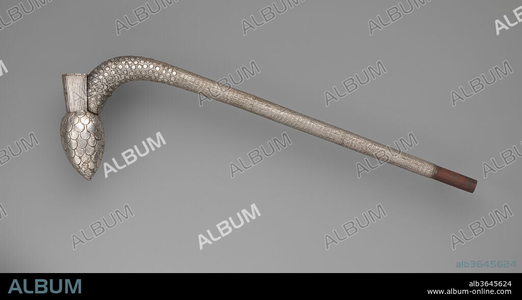 Royal Scepter (Makpo). Culture: Fon peoples, Danhomè Kingdom. Dimensions: H. 24 7/8 × W. 8 1/8 × D. 2 1/8 in. (63.2 × 20.6 × 5.4 cm). Date: 19th century.
This arm-length scepter is composed of a wooden core wrapped in precious silver. The outer metal is applied as thin overlapping sheets of silver nailed to the surface. The wood end of the staff is now exposed but was probably originally covered in metal as well. The straight shaft of the scepter progressively thickens and curves at an almost ninety-degree arc. Reinforcing this contour and adorning the extremity of the staff is a bulbous finial representing a pineapple carved from a separate piece of wood and affixed to the shaft with a metal peg. Stamped and punched patterns adorning the entire silver surface subtly underscore the different sections of the scepter: tight, short rows of dotted lines on the straight section of the shaft; small indented circles with flurries of small dots on the upper arched part; larger semi-circles in the shape of overlapping leaves on the finial; and straight vertical lines extending upwards as the pineapple leaves. A round sheet of silver, the size of a small coin, is affixed with four nails to the front of that upward extension. 
This scepter (known among the Fon peoples as makpo, or staff of fury) belongs to a corpus of silver works that served as objects of power and prestige to rulers of the Fon Kingdom of Danhomè in present-day Republic of Benin, a West African nation state. In the eighteenth and nineteenth centuries, the Kingdom of Danhomè prospered as a major political power and commercial center situated off the Gulf of Guinea. It gained much of its power by playing an active role in the international slave trade. Since the seventeenth century until the conquest of the kingdom by France in 1894, generations of Danhomè kings served as great patrons for the arts, often commissioning items to enhance their own royal status, or to commemorate their predecessors. They oversaw the development of a rich iconography visible until today in a diverse array of idioms, from scepters and other personal regalia to architecture. 
Art historian Suzanne Preston Blier explains that the scepter's overall shape derives from a genre of throwing-stick weapons introduced to Danhomè in the 17th century under the dynasty's founder, Huegbadja (reigned c. 1645-1685). A distinctive royal symbol typically adorns such scepters to link them to either the commissioning or commemorated king. This scepter's finial in a shape of a pineapple connects it to King Agonglo, who reigned from 1789 until 1797. In the Fon language, the word for pineapple is agon, which because of its similarity to the name Agonglo became a pictogram for the ruler's name. Renowned for his art patronage, Agonglo is credited with developing the artistic tradition of the royal scepters. A century later, Agonglo was established as King Gbehanzin's sponsoring ancestor and protective spirit (djoto). Gbehanzin ruled from 1889 until 1894 and during this time, commissioned this work to honor his ancestor (Blier 1998). 
Such scepters in general, and the specific imagery seen here, signifies the passage of royal power through dynastic succession in the Kingdom of Danhomè. Makpo scepters further epitomized royal power. A key visual marker during public appearances, a king often carried such a scepter over his right shoulder, with the curved end hooked over his shoulder blade. The identification of a given scepter with a specific ruler was so strong that it could stand in place of the king on court business, and its image could function as a personification of the royal presence. 
From the 17th century on, Danhomè royalty promoted establishment of guilds of specialized artists, who occupied compounds in the sprawling royal palace of Abomey, the kingdom's capital (Beaujean-Baltzer éd. 2009). Jewelers and smiths from the royal Huntondji artists' compound were responsible for crafting objects in precious silver for members of the royal family as well as for the devotees of important Fon deities. The material itself came from European sources, including silver coins brought as gifts in large quantities for Danhomean kings during the 18th and 19th centuries (Blier 2008). Melted and reused by Danhomè artists, the silver came to signify symbolically the Kingdom's appropriation of wealth and power. 
Many of the historical arts produced in West and Central Africa comprised works either carved of a single piece of wood or metalwork cast to shape. By contrast, arts of Danhomè are often made of separate pieces and diverse materials. Suzanne Preston Blier demonstrates that artists in the kingdom developed a unique art of assemblage (Blier 2004). Across media, from scepters to asen altar staffs and appliqué textiles, works combine disparate elements to create composite forms. Both the constructed nature of Danhomè works and the extensive use of silver, contributed to setting the kingdom's creations apart from arts fashioned in two contemporary powerful neighboring polities, the Asante Kingdom in present-day Ghana, and the Benin Kingdom, in present-day Nigeria. The arts thus developed affirmed the Danhomè kings' desire for distinction. 
Arts of assemblage developed by Fon artists, through their incorporation of foreign imagery, materials, and forms, can be understood as artistic responses to the cultural and political appropriation central to Danhomean kings' expansionist ambitions (Blier 2004 and 2008). The cumulative and composite nature of this royal scepter, made of two pieces of wood and multiple thin sheets of imported and re-used silver, reflects this artistic practice and is symptomatic of deeper social and political implications.