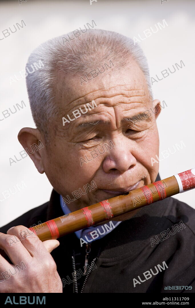 Man plays a Dizi flute in the park by the City Wall, Xian, China.
