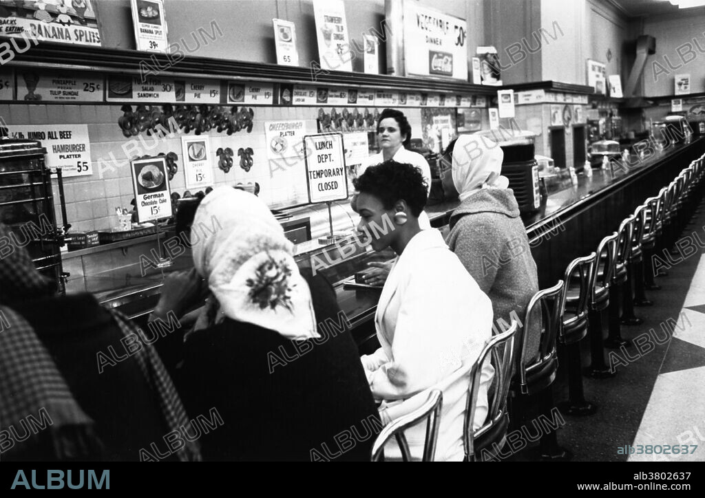 February 9, 1960, Charlotte, NC. The very first sit-in took place a week earlier in Greensboro, NC. The Charlotte sit-in was not well covered at the time, but it marked the fact that what had happened in Greensboro was spreading to other Southern cities. It was the college students from Johnson C. Smith University who took park in the sit-ins. These students also started picketing a downtown theatre to allow blacks to sit downstairs in the theater. The sit-ins had taken store management by surprise; the waitresses didn't know what to do and just faded away, leaving the students sitting at the counters. The students had told the chief of police what they were going to do in advance. The chief of police had promised to make no arrests if they did it in an orderly way and he kept his word; no police ever appeared at the Charlotte sit-ins and there were no arrests. After a few hours, the students left and the stores put up signs saying their lunch counters were temporarily closed. On July 3rd, the counters at Woolworth's were reopened to everyone. NOTE: The waitress left soon after this photo was taken.