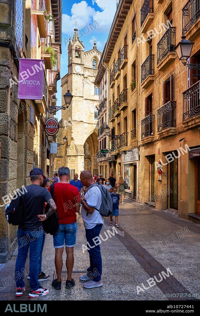 Turistas paseando por la Parte Vieja, al fondo Iglesia de San Vicente, Donostia, San Sebastián, Gipuzkoa, País Vasco, España, Europa, Adentrarse en la Parte Vieja es conocer el verdadero centro social de Donostia, sus calles empedradas como la del 31 de Agosto, que conmemora el incendio ese día de 1813, están llenas de bares para disfrutar de los mejores pintxos de la ciudad, y sus edificios emblemáticos como la Basílica de Santa María del Coro y la iglesia de San Vicente son de gran atractivo e interés,.