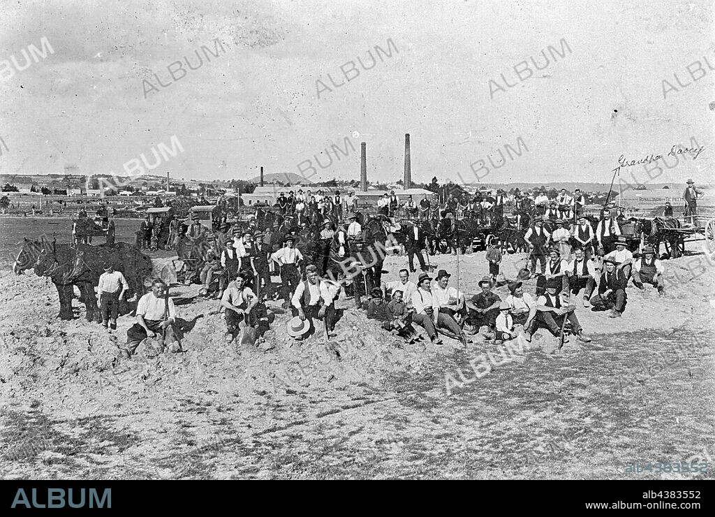 Negative - Ballarat Showgrounds, Victoria, circa 1930, Men and horses on a working bee at the Ballarat Showgrounds. An arrow points to a man identified as 'Grandpa Davey'. The chimneys of a mill can be seen in the background.
