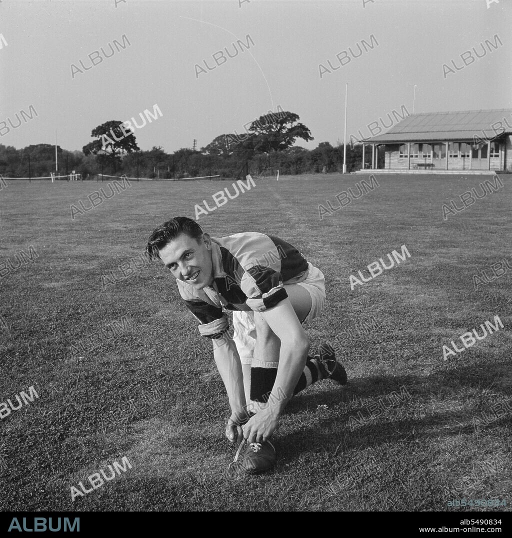 JOHN LAING PLC. Gordon Johnson, a member of the Football Section of Laing's Sports Club, Barnet, London, 07/09/1955. Gordon Johnson, a member of the Football Section of Laing's Sports Club, smiling at the camera as he ties his shoe laces at a sports ground. This image was published in the October 1955 edition of Laing's monthly Team Spirit newsletter, in the 'Sports Personality' section. The article welcomes Gordon Johnson back to the team after completing a two year period of National Service in the Navy. Gordon had played for the club since 1949, and was a member of the first eleven.