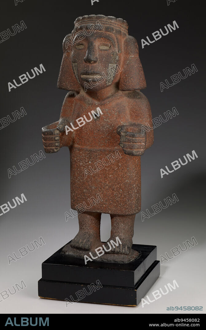 Chalchiuhtlicue, c. 1200-1521, 20 x 8 3/8 x 6 5/8 in. (50.8 x 21.27 x 16.83 cm) (without base)23 x 8 3/8 x 8 1/8 in. (58.42 x 21.27 x 20.64 cm) (with base), Gray basalt, red ochre, Mexico, 13th-16th century, Chalchiuhtlicue (Chal-chee-oot-LEE-kway), literally 'She of the Jade Skirt,' is the Mexica (meh-SHEE-kah) goddess of water and the wife of rain god Tlaloc (TLAH-loak). She is identifiable by her distinctive wide headband with large tassels. Precious stone or shell was once inlaid into her eyes, the incisions in her cheeks, and the cavity in her chest. However, this sculpture assumes the pose characteristic of another important Mexica goddess. Her pose, standing with her hands extending outward as if she were holding something, is typical of the corn goddess Chicomecoatl (Chee-koh-may-KOH-atl). As Chicomecoatl, she would have likely held small ears of an ancient variety of corn, which are now lost. Both goddesses are associated with fertility. A sculpture like this one would have been the focal point of a shrine.