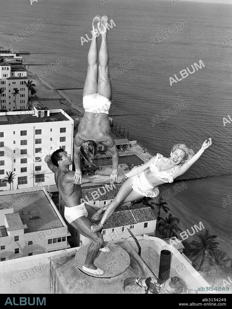 Miami Beach, Florida:  November 15, 1951 The Wayne-Marlin trio rehearses atop the chimney of the Lord Tarleton Hotel. George Wayne Long holds Glen Marlin Sundby and his sister Dolores with no apparent effort twenty stories above the ground.