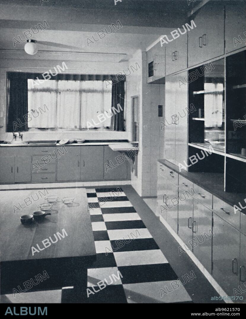 'R. W. Symonds and Partner, L. & A.R.I.B.A. - Kitchen: Putty-coloured cellulosed fiitments, stainless steel sinks, and a teak plate-rack in the scullery of a house in Gloucester Square, London', 1939. From Decorative Art 1939 - The Studio Year Book, edited by C. G. Holme. [The Studio Ltd., London, 1939].