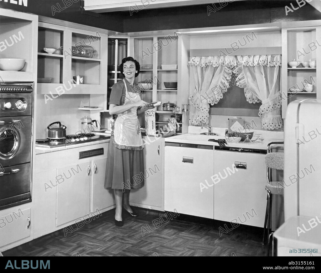 United States: c. 1950.  A woman wearing an apron in the kitchen of a model home making a sandwich with Wonder Bread.