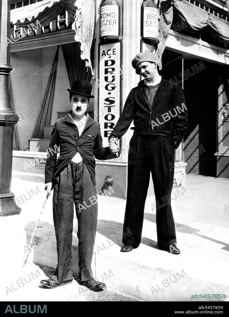 Charlie Chaplin Meets "The Kid" Grown Up -- Jackie Coogan (right), whom Charlie Chaplin made famous in 1921 as "The kid," is shown visiting the famous film comedian in Hollywood recently. Jackie had never seen the picture which started him on the road to fame, so Chaplin ran in off for him. May 06, 1935. (Photo by Associated Press Photo).