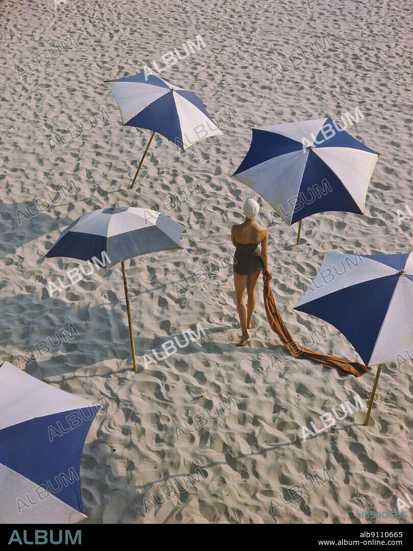 Rear View Portrait of Woman in One-Piece Swimsuit surrounded by Umbrellas on Beach, Toni Frissell Collection, December 1948.