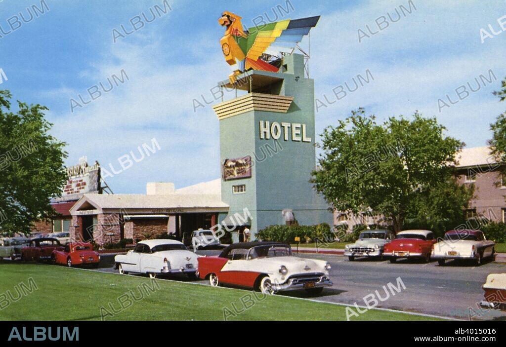 Thunderbird Hotel, Las Vegas, Nevada, USA, 1956. Vintage postcard showing the exterior of the entrance to the Thunderbird Hotel. A large colourful thunderbird sits atop a an aqua-blue tower. A brick port cochere encloses the entrance and parked cars line the drive. The Thunderbird resort was the fourth hotel and casino to be built on the Las Vegas Strip. It was open from 1948 until 1992. The Turnberry Place complex occupies the site today.