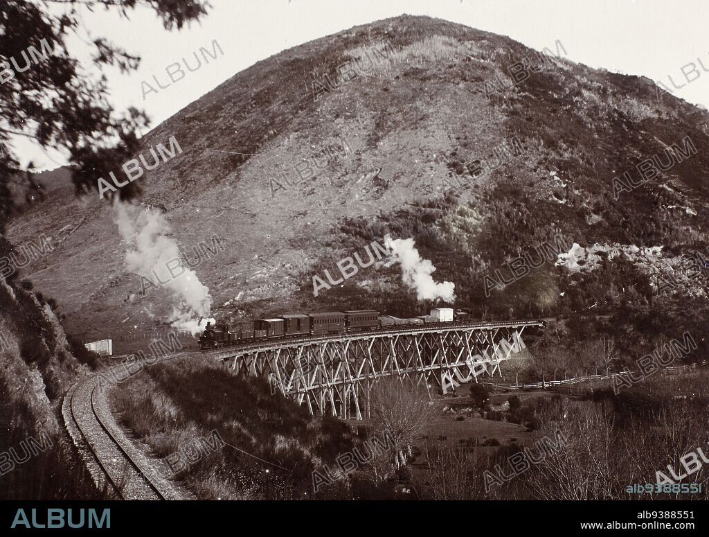 Rail bridge, South of Picton, Muir & Moodie studio, photography studio, circa 1900, Dunedin, photography, Depicts a steam train travelling over a wooden bridge in front of a large hill. G Class locomotives on each end of the train.