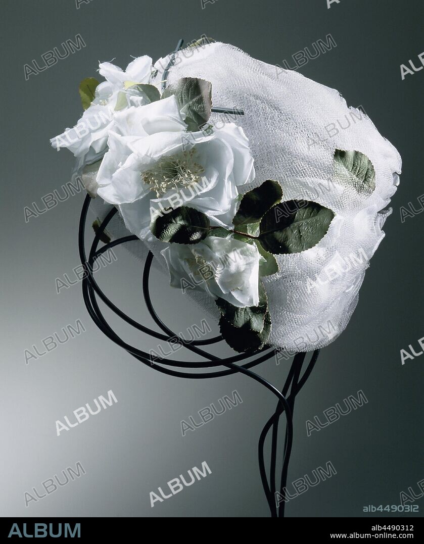 Hat made of draped, light blue tulle decorated with light blue rose petals and green leaves, light blue tulle decorated with light blue rose petals and green leaves. Model: The tulle is draped over an interior of light blue mesh. Decoration: flowers and leaves are placed between the draped tulle. At the front a symmetrical corsage of light blue roses with green leaves and black stems., anonymous, Netherlands (possibly), c. 1955, binnenwerk, draperie, bloemblaadjes, bloemstelen, h 15 cm × d 22 cm.