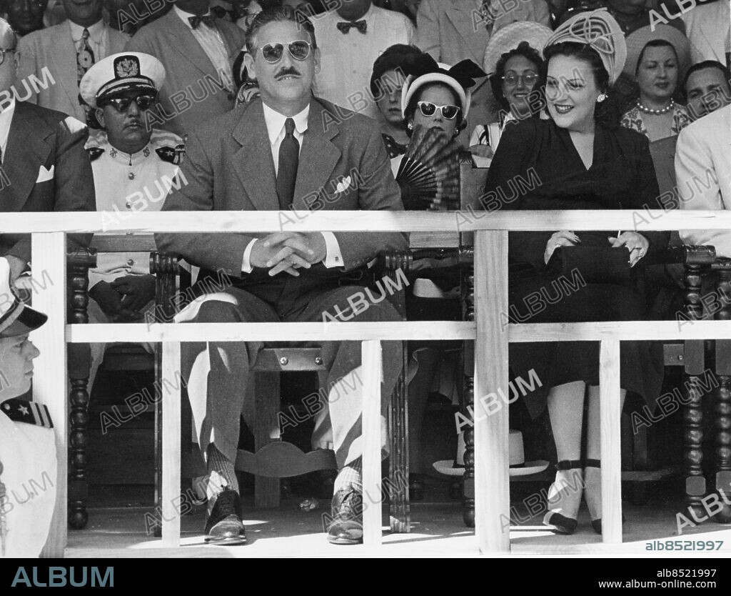Orig. bildtext... CUBA'S NEW PRESIDENT REVIEWS INAUGURAL PARADE Havana, Cuba....Dr. Carlos Prio Socarras, new president of Cuba, sits with his First Lady in the reviewing stand watching the military parade that was a feature of his inauguration ceremonies. President Prio succeeded President Grau San Martin. Anm. C P Socarrás, president på Cuba 1948-1952 Solglasögon Åskådare Presidentpar Officerare Mustascher Installation Leenden Societet CD250 persons: Carlos Socarras sites: CUBA ;HAVANNA.