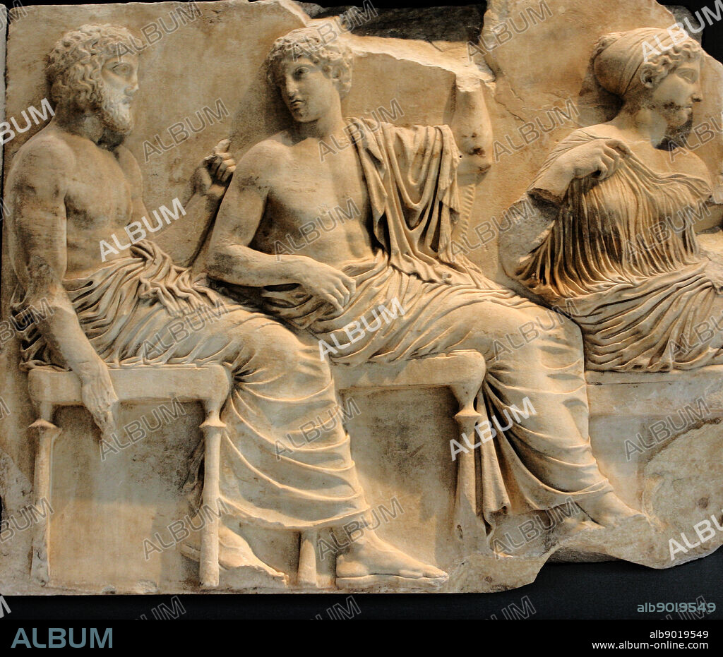 A young winged goddess, Iris or Hebe, messenger of the diving couple Zeus and Hera, stands next to Hera turning toward the procession, while she arranges her wind blown hair with her left hand. Hera turning towards Zeus holds the edges of her himation, which covers her head in the gesture of a bride revealing herself to her husband.