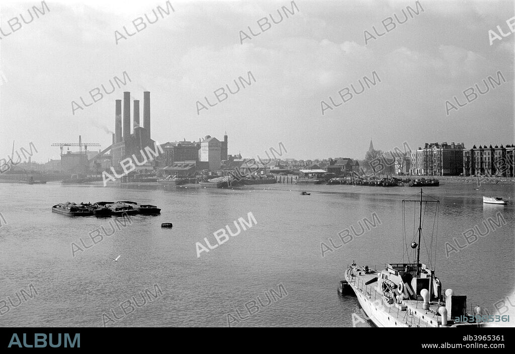 Fulham Power Station, London, c1945-c1965. Fulham Power Station was opened in 1936. It is seen here from Wandsworth Bridge. Coal was delivered by river, as the four barges in mid stream testify. The Power Station has since been demolished.