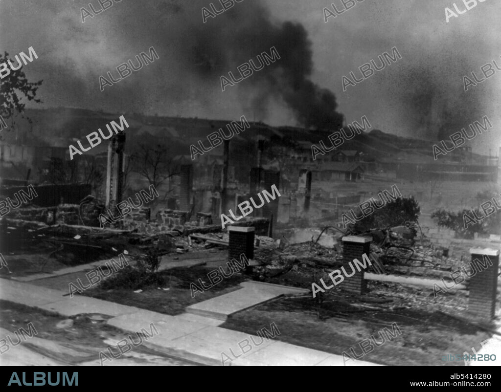 Smoldering ruins of African-American homes. The Tulsa race riot of 1921 began over Memorial Day weekend after 19-year-old Dick Rowland, a black shoeshiner, was accused of assaulting Sarah Page, a 17-year-old white elevator operator. After he was taken into custody, a group of armed black men, worried about a possible lynching, rushed to the police station where they encountered a crowd of white men and women. Shots were fired, and 12 people were killed, 10 white and 2 black. Mob violence exploded. About 10,000 black people were left homeless, and property damage amounted to more than $1.5 million in real estate and $750,000 in personal property ($32 million in 2019). Alvin C. Krupnick Company, 1921.
