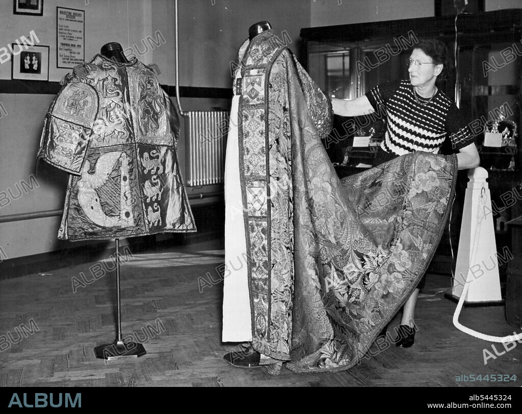 Kent Sees Coronation Robes and Crown Jewels Replicas Mrs. M.M. Beaumont of Sittingbourne, wife of the Secretary to St. Johns Order and Area Commander prepares the Coronation cope of the the Archbishop of Canterbury. On left is the tabard of Sir Gerald Woods Wollaston, KCB, KCVC, Norroy and Ulster King at Arms. Viscountess Allerby today opened an exhibition of Coronation robes and or replicas of the Crown jewels at Dunk memorial Hall, Maidstone, Kent, held by the council of the Order of St. John to raise funds for their cadets. The exhibition will be held also at Canterbury and Tunbridge wells. October 04, 1952. (Photo by Fox Photos).