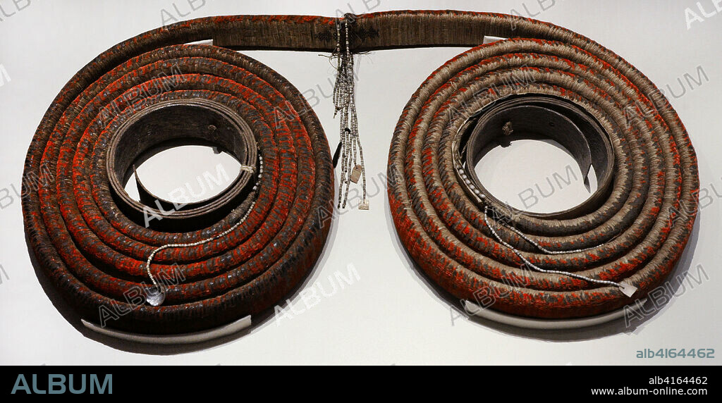 Tevau, also called "feather money". It consisted of a strip of plant fiber about 7 cm. wide and 10 m. long, wheel-shaped threaded on two rings of tree bark, being woven on one side with rows of tiny red feathers superimposed, of a honey-eating bird called Cardinal Myzomela. Its manufacture was very complex and was passed down from father to son, since its magical components were not within the reach of everyone. These feather rolls were used as money for ritual payments, such as the marriage ceremony, and to acquire high-value goods. They were carefully stored in dry and warm places to preserve their flexibility and color. Despite the massive influx of Australian coins and banknotes since World War II, this form of money continued to be used for traditional payments until at least the 1950s. In 1975, the existing tevau were declared cultural heritage, prohibiting the government from exporting them outside the islands. 19th-20th century. Santa Cruz Islands (Solomon Islands, Oceania). National Archaeological Museum. Madrid. Spain.