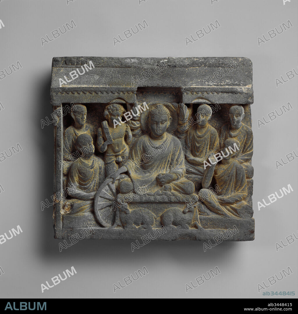 Buddha's First Sermon at Sarnath, 2nd century, Pakistan (ancient region of Gandhara), Gray schist, H. 11 1/4 in. (28.6 cm); W. 12 1/4 in. (31.1 cm); D. 2 in. (5.1 cm), Sculpture, The Buddha is shown teaching the first sermon to five ascetics who become monks; in this way, he establishes the monastic order. The Buddha reaches down to set in motion the wheel of the law—a well-established symbol of Buddhist teaching, or dharma.