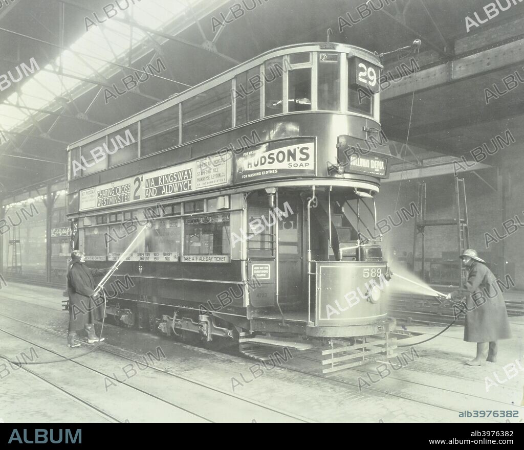 Transport workers washing a tram at the Holloway Car Shed, London, 1932. Interior of a tram shed with men using hoses to wash a Route 29 tram which has an advertisement for Hudson's soap.