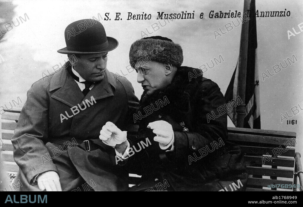 Gabriele D'Annunzio with Benito Mussolini. In the garden of Cargnacco Villa (the Vittoriale) Gabriele D'Annunzio, Italian poet and writer, speaking with Benito Mussolini on a bench. Gardone Riviera, May 1925.