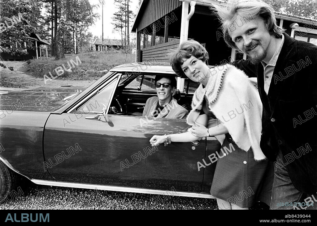 JÄRNA 1966-06-07. Reportage inför tv-sändningarna från Le Mans-loppet. Tidningen RiR-TV har sammanfört tre personer med stort intresse för motorsport: tävlingsförare Barbara "Bra-Bra" Johansson, konstnär John Erik Franzén och författare Lars Görling. Fr v Lars Görling i bil, Barbara "Bra-Bra" Johansson och John Erik Franzén utanför Görlings hem i Järna. Foto: Bo-Aje Mellin / RiR / SVT / Kod: 5600 RiR 18113 sv/v neg Rep publ i RIR 25/66 s.10-11 Kvinnliga rallyförare John-E Franzén John E. Franzén persons: BARBARA JOHANSSON;LARS GÖRLING;JOHN ERIK FRANZÉN sites: SVERIGE;JÄRNA.