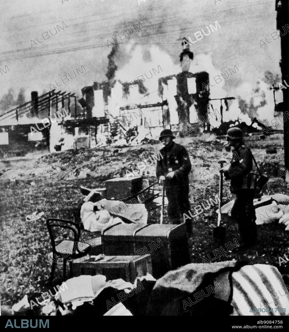 WW2: German invasion of Russia. Nazi pillagers survey the spoils, while a home burns behind them.