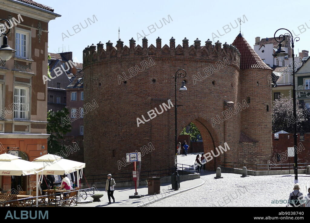 Photograph of the Warsaw Barbican (Barbakan Warszawski) is a barbican (semi-circular fortified outpost) in Warsaw, Poland, and one of few remaining relics of the complex network of historic fortifications that once encircled Warsaw. The barbican was erected in 1540 in place of an older gate to protect Nowomiejska Street. It was designed by Jan Baptist the Venetian, an Italian Renaissance architect. Dated 21st Century.
