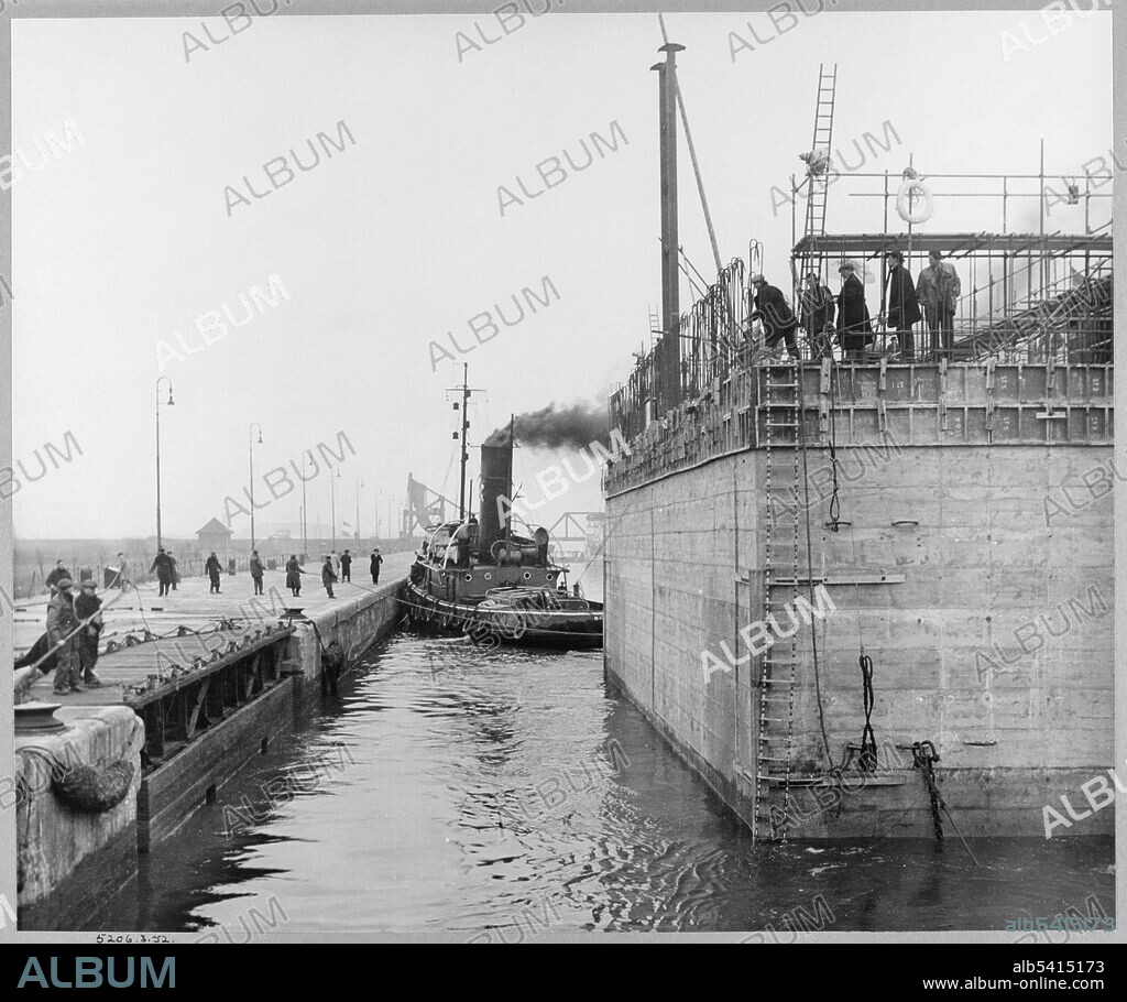 JOHN LAING PLC. A view of the cooling water intake caisson for Coryton Oil Refinery leaving Tilbury Dock to begin its journey down the Thames. During the Second World War, John Laing & Son Ltd had built some of the floating caissons for the Mulberry harbour which were used in the D-day landings. This 4,200 ton concrete water intake caisson was built along the lines of the Mulberry harbour and was towed 8 miles down the Thames from Tilbury Dock to be installed as part of Coryton Oil Refinery on the 14th March 1952. It was built between 1951 and 1952. For photographs of its construction see albums JLP01/01/063 - JLP01/01/064.