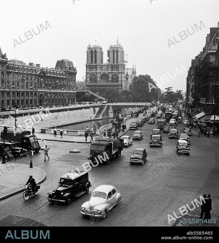 Paris (Frankreich), Quai Saint-Michel. Straßenbild; im Hintergrund Notre Dame, links vorne die Pont Saint-Michel und links auf der Ile de la Cité die Polizeipräfektur. Foto, undat. (um 1955?). Aus einer Serie: Paris - Circulation (Verkehrsszenen).