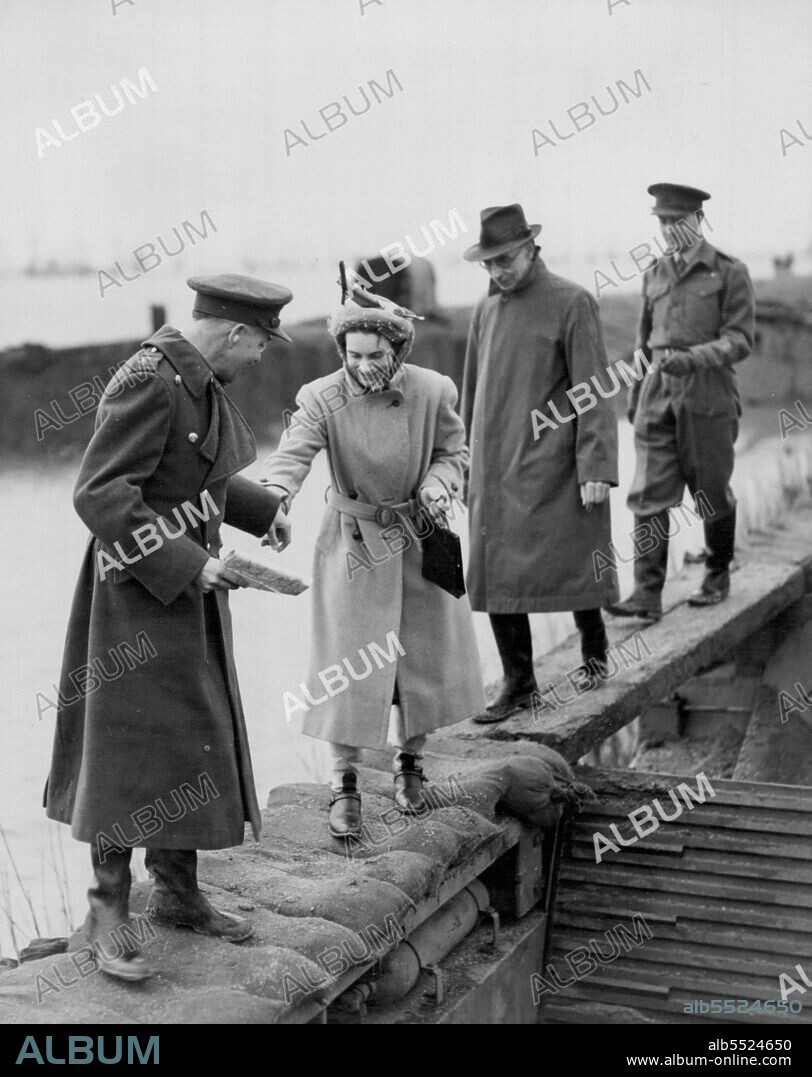 Duke And Duchess Of Gloucester See Fenland Floods: Lt. Col. M. Morling, in charge of the Earith gap operation, assists the Duchess of Gloucester as she walks over one of the Neptune tanks closing the gap.
H.R.H. The Duke Of Gloucester, Senior Councillor of State, accompanied by the Duchess, yesterday (Sunday) visited the flooded Fens, where thousands of acres of farmland were inundated. They inspected the  gap in the bank of the River Ouse at Earith, closed by Royal Engineers who sank Neptune tanks in the breath. March 31, 1947.