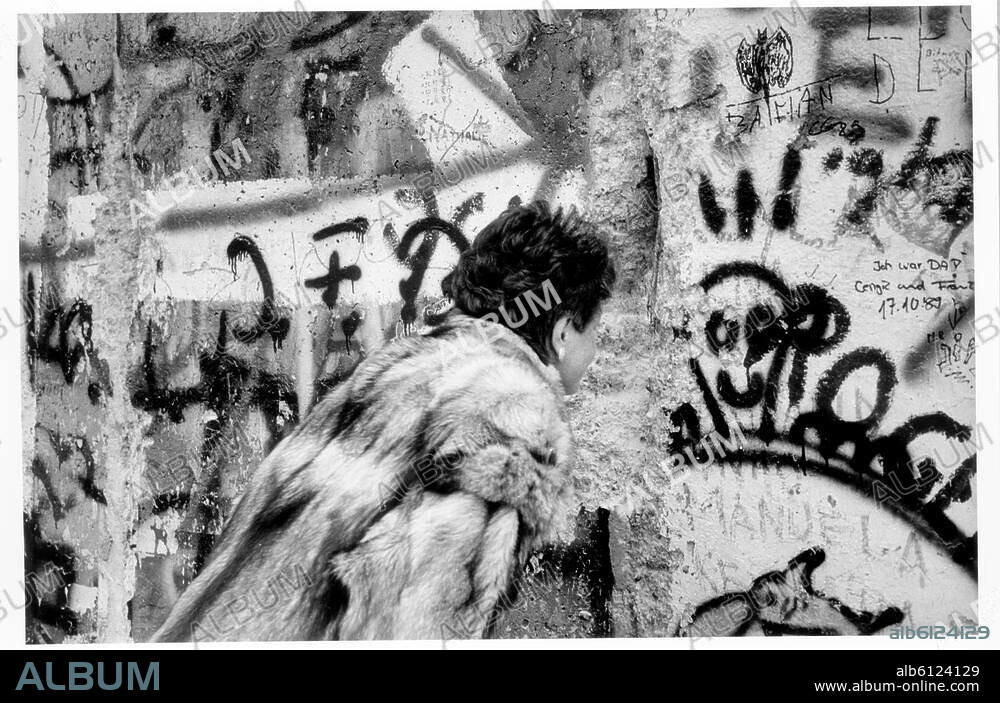 Berlin, 10./11. November 1989. Nach Öffnung der DDR-Grenzen zum Westen (9.11.1989).-Eine Frau schaut durch ein Loch in der Mauer.-Foto.