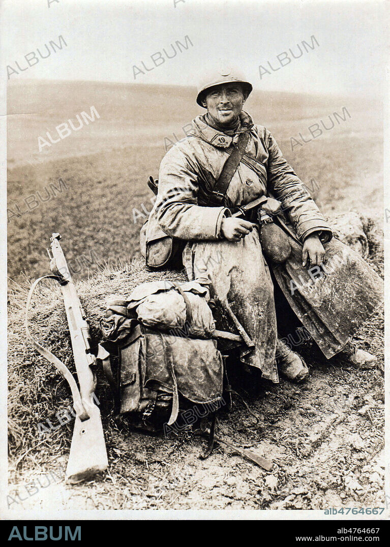 Poilu se reposant avec son paquetage pendant la 1ere guerre mondiale, assis sur le bord de la route. Photographie anonyme vers 1915. Credit : Collection Avant-Demain/Kharbine-Tapabor.