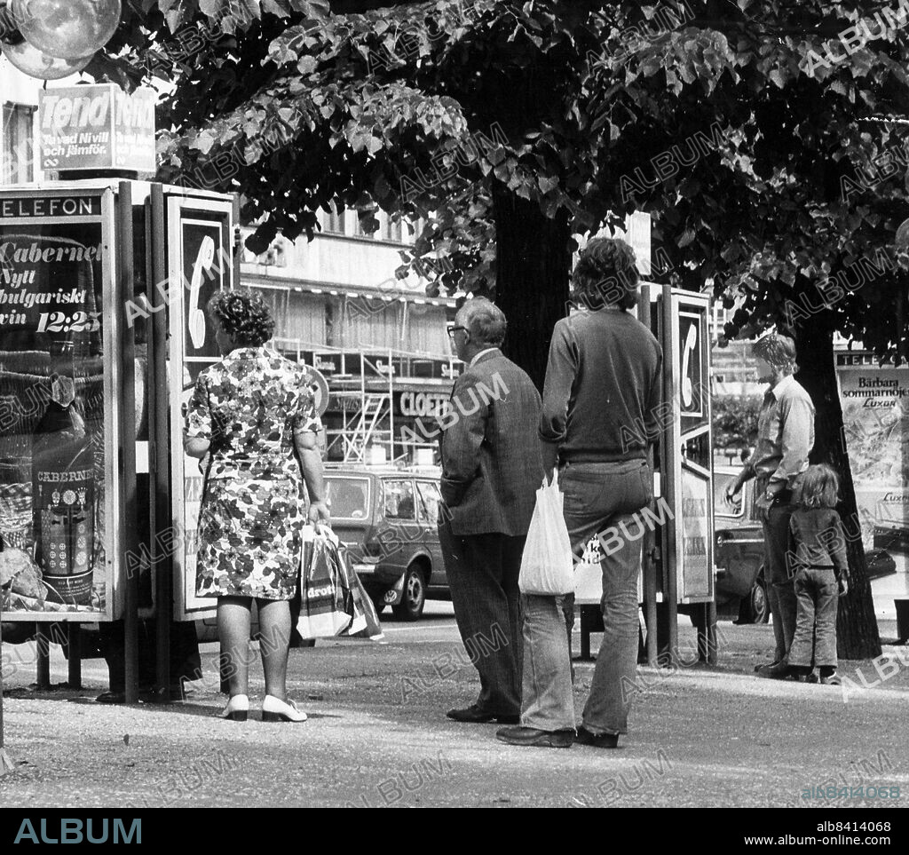 STOCKHOLM 1975-07-25. Stans populäraste telefonkiosk. Ryktet säger att man kan ringa vart som helsthur länge som helst för 25 öre!. En telefonkiosk i Kungsträdgården. Populärast i stan. Folk står i kö för att ringa från den. Har de också hört talas om dess hemlighet eller är det bara en slump att de står just där? Det går nämligen att rykte om just den här telefonkiosken. Ryktet säger att du kan lura televerket i den. Du knallar bara in, lyfter luren, stoppar i en 25-åring och sen är det fritt fram att ringa vart som helst i världen hur länge som helst. Foto: DN / TT / kod 192. ** SVD OUT **.