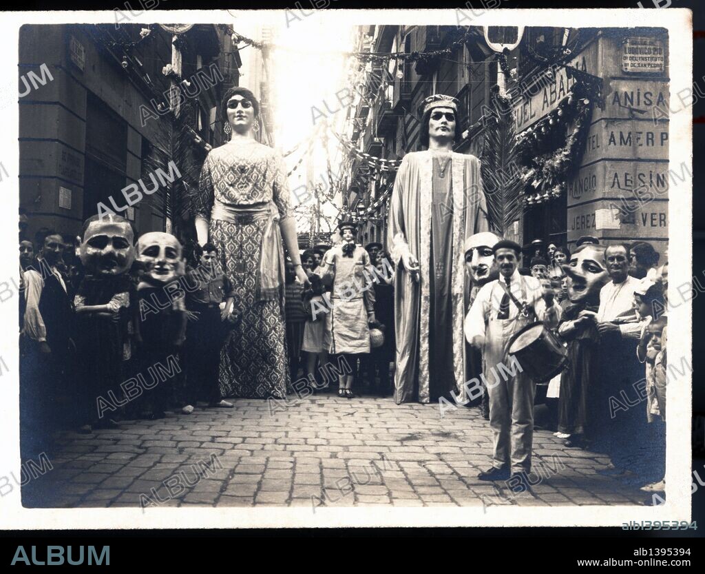 Gigantes de Barcelona, representando a Jaume I y Violant de Hungria, acompañados de los cabezudos por las calles de la ciudad. Años 1930.