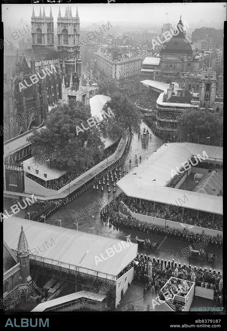 MINISTRY OF WORKS. Coronation of Queen Elizabeth II, Parliament Square, City of Westminster, Greater London Authority, 02-06-1953. An elevated from the Clock Tower at the Palace of Westminster looking down towards Westminster Abbey, showing crowds of people in temporary stands, watching the coronation procession of Queen Elizabeth II.