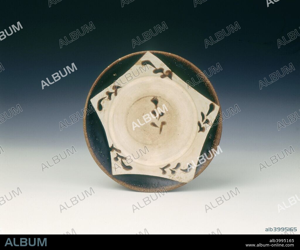 Yaozhou dish, Late Tang dynasty, Shaanxi province, China, 9th-early 10th century. Shallow flat-rimmed Yaozhou dish with Cizhou type decoration of brown painted abstract leaf designs on a reserved star-shaped background created by four dark brown glazed splashes on the rim over a white slip overall.