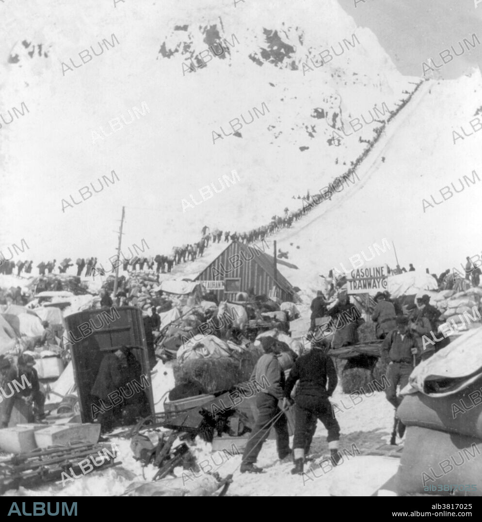 Bound for the Klondike Gold Fields, Chilcoot Pass, Alaska. The Klondike Gold Rush was a migration by an estimated 100,000 prospectors to the Klondike region of the Yukon between 1896-99. Gold was discovered by local miners on August 16, 1896 and, when news reached Seattle and San Francisco, it triggered a stampede of would-be prospectors. To reach the gold fields most took the route through the ports of Dyea and Skagway in Alaska. Here, the Klondikers could follow either the Chilkoot or the White Pass trails to the Yukon River and sail down to the Klondike. Each of them was required to bring a year's supply of food by the Canadian authorities in order to prevent starvation. In all, their equipment weighed close to a ton, which for most had to be carried in stages by themselves. Together with mountainous terrain and cold climate this meant that those who persisted did not arrive until summer 1898. Mining was challenging as the ore was distributed in an uneven manner and digging was made slow by permafrost. In the summer of 1899, gold was discovered around Nome in west Alaska, and many prospectors left the Klondike for the new goldfields, marking the end of the rush. Gold mining activity lasted until 1903. Cropped stereograph card, Keystone View Company, 1898.