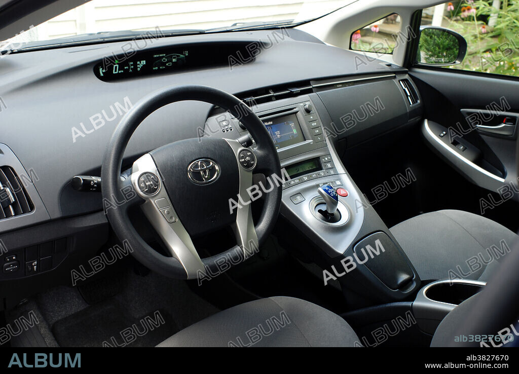 Interior of a Generation III Toyota Prius Hybrid, showing dashboard, displays, and controls. Hybrid cars utilize a battery to store energy generated by braking and coasting and use it to drive an electric motor in tandem with a small gasoline engine. Together they provide power to drive the car, while using less gasoline than an internal combustion engine alone.