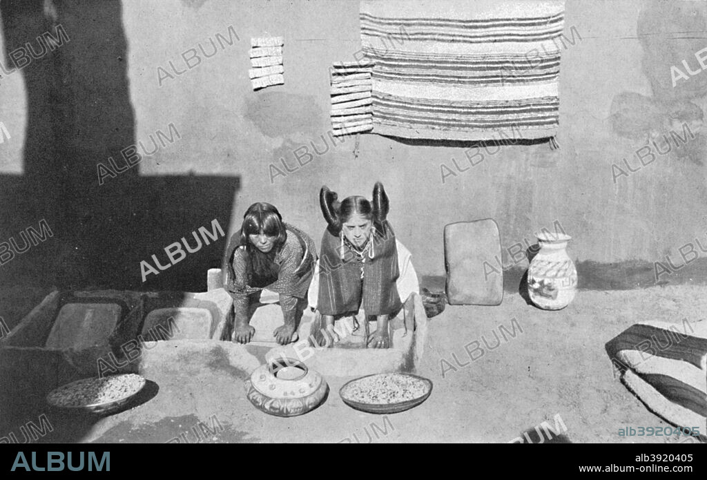 Hopi Indian women grinding corn meal, Walpi, Arizona, 1912. The  distinctive hairstyle of the woman on the right identifies her as being unmarried. From The Living Races of Mankind, Vol. II. [Hutchinson & Co, London, 1912].