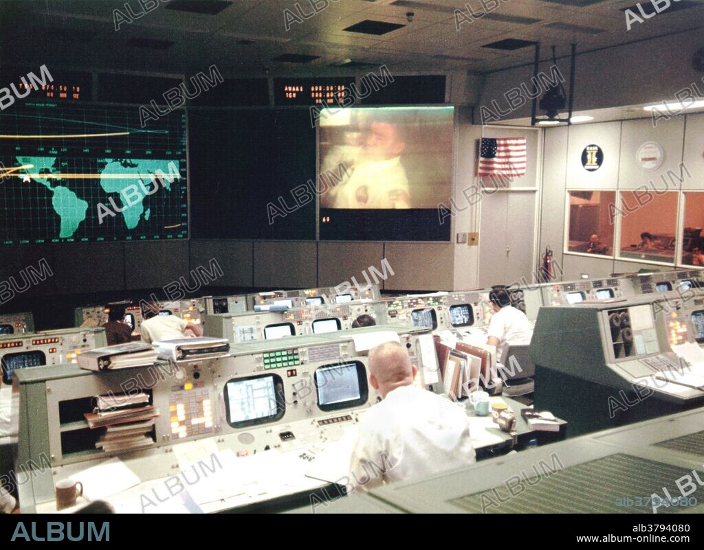 Overall view of the Mission Operations Control Room in the Mission Control Center at the Manned Spacecraft Center, during the fourth television transmission from the Apollo 13 spacecraft while en route to the Moon. Eugene F. Kranz (foreground, back to camera), one of four Apollo 13 Flight Directors, views the large screen at front of MOCR. Astronaut Fred W. Haise Jr., lunar module pilot, is seen on the screen. The fourth television transmission from the Apollo 13 mission was on the evening of April 13, 1970. Shortly after the transmission ended and during a routine procedure that required the crew to flip a switch that stirred one of the cryogenic liquid oxygen tanks, an explosion occurred that ended any hope of a lunar landing and jeopardized the lives of the three crew members.