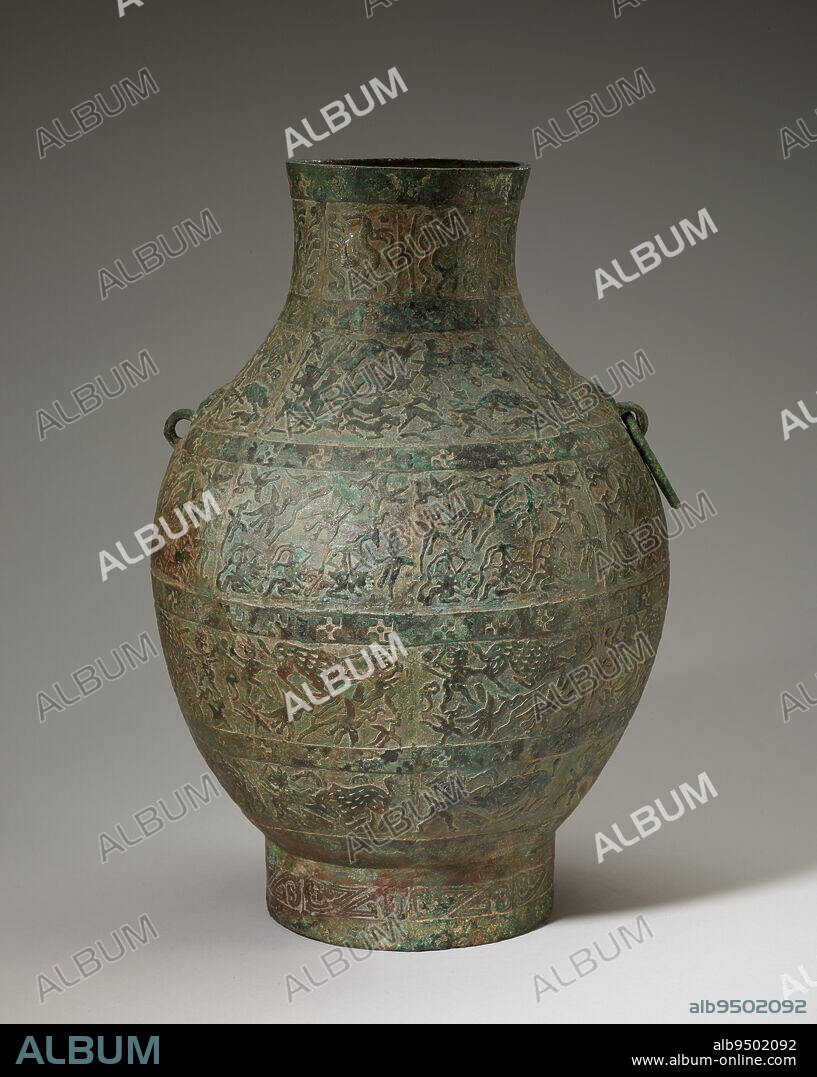 Hu wine vessel, 5th century BCE, 13 7/8 × 9 3/8 in., 6.4 lb. (35.24 × 23.81 cm, 2.9 kg), Bronze, China, 5th century BCE, This storage vessel is one of an important group of hunting-scene hu. They show the influence of the nomadic art of Chinas northern frontier. The four major bands depict men hunting birds, deer, boars, and tigers with spears, knives, and bows. Panels on the vessels shoulders show an archer shooting from the back of a four-horse chariot with driver. These pictorial scenes of human activity represent a revolutionary departure in bronze art. Previously, during the Shang and Zhou periods, sacred symbols and stylized animals were formally arranged with regard to hierarchy and strict symmetry. The subject here appears secular rather than religious.