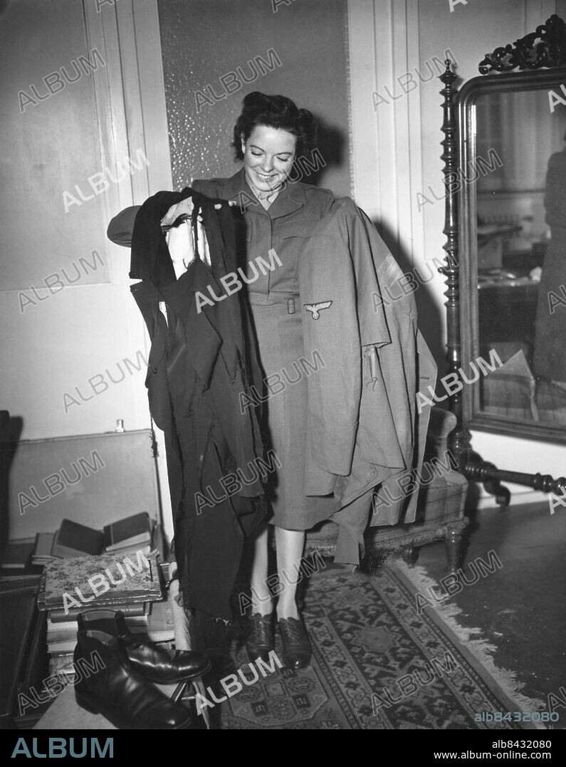 Orig. bildtext... HITLER'S CLOTHES WHAT THE WELL-DRESSED FEUHRER WORE TO A BOMBING Frankfurt, Germany. Wac. sgt. Virginia M. Wood of Lorton, Va., is shown holding the pants and jacket which Adolf Hitler is supposed to have worn during the bombing attempt upon his life on July 20, 1944. The clothing and other mementos and valuables were found among effects of Eva Braun on a bavarian estate. Eva was Hitler's mistress for about ten years and was probably wed to him just before they died in a suicide pact. persons: Virginia Wood ;Adolf Hitler* sites: TYSKLAND ;FRANKFURT.