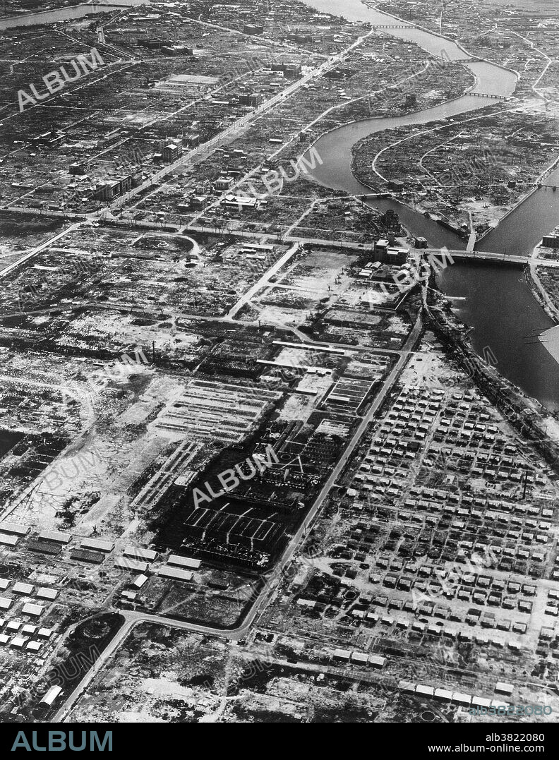 An aerial view of Hiroshima, Japan, one year after the first atomic bomb was dropped on August 6th, 1945. This single nuclear bomb (nicknamed "Little Boy") destroyed almost all of the city's houses and buildings and instantly killed 80,000 people. The death toll continued to rise over the years, as survivors contracted cancers associated with radiation; ultimately the bomb claimed over 200,000 lives. Here, one year after the bombing, the T-shaped bridge, which was the aiming point for the bomb, is still standing in a dilapidated condition. Newly-built houses can be seen in the foreground.