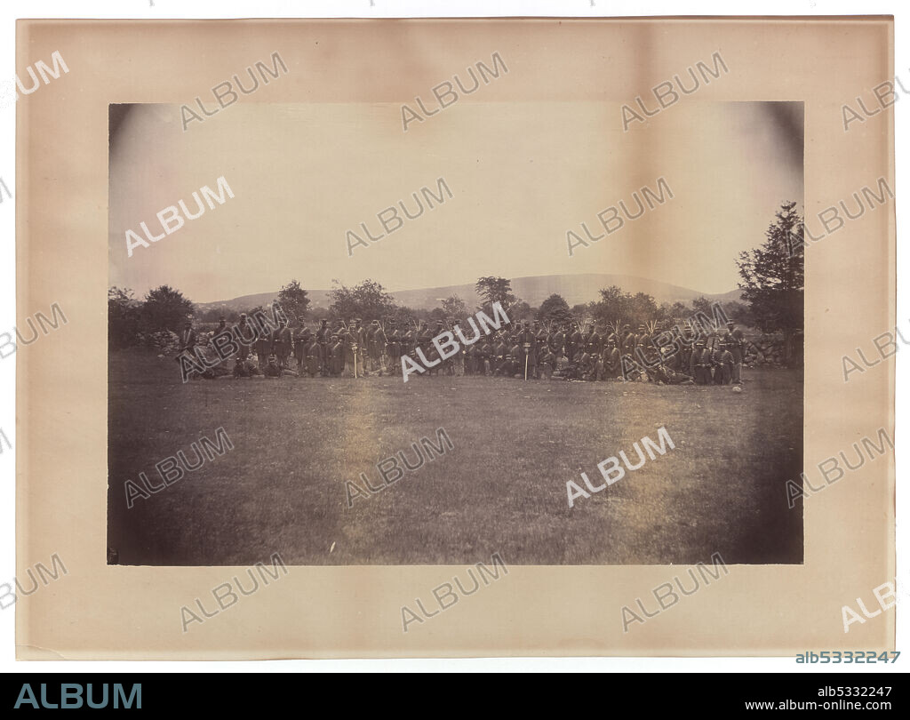 A photograph of 59 members of the 55th Massachusetts Infantry in uniform. The enactment of the Emancipation Proclamation by US President Abraham Lincoln on 1 January 1863 opened the way for the enlistment of free men of colour and newly liberated slaves to fight for the Union Army during the American Civil War. The image features two (2) rows of African-American soldiers, with the back row of men standing and the front row of men either kneeling or lounging. The soldiers stand outside with a row of trees in the background. The image is on photo paper and has been adhered to a larger backing. The image has discoloration throughout, especially on the back. There are no inscriptions, front or back.