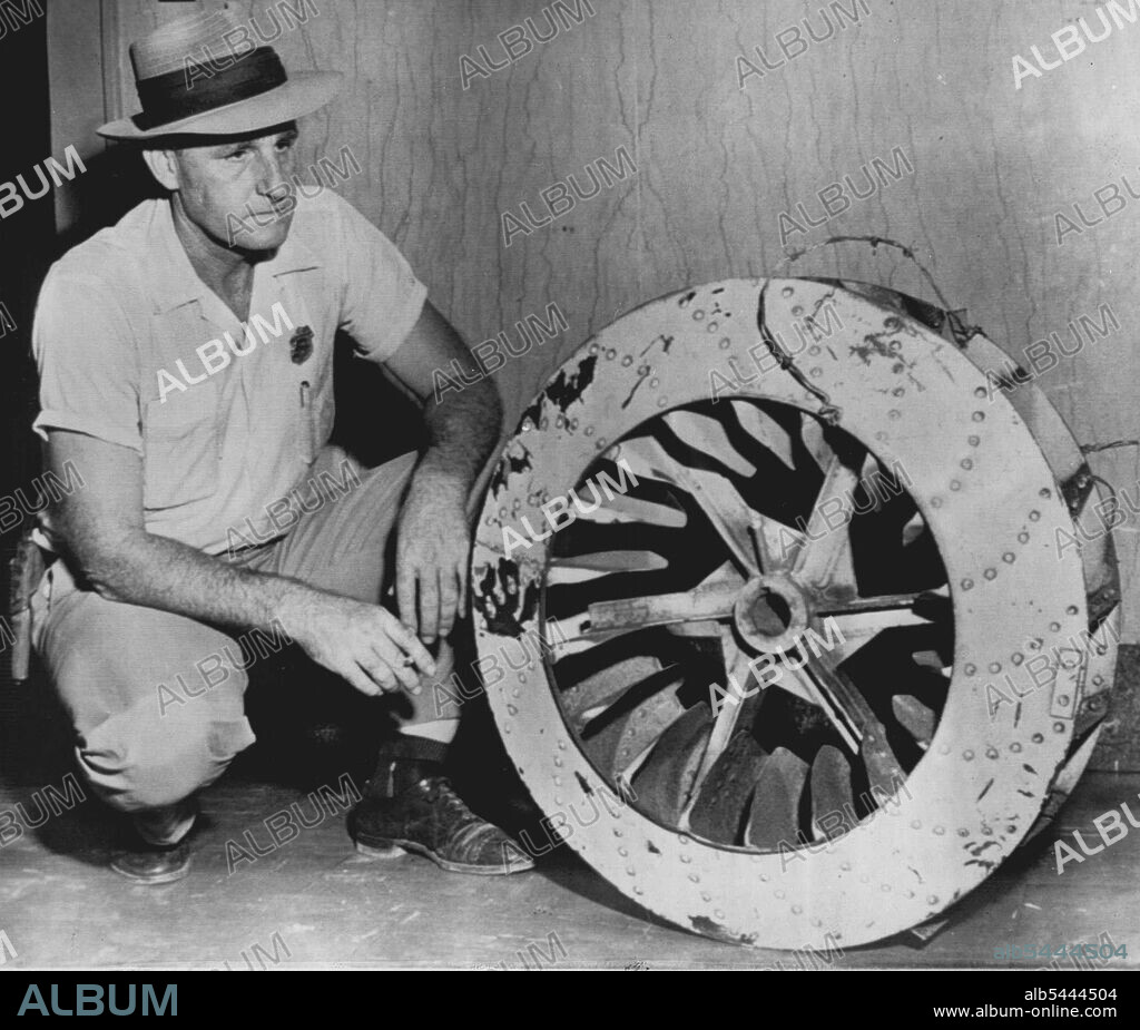 Fan Used As Weight -- Leflore County Deputy Sheriff John Ed Cothran examines the huge cotton gin fan used to weight down the body of 15-year-old Emmet Louis Till in the Tallahatchie River about 25 miles north of here. The negro boy's body was found yesterday, with the barbed wire used to tie the body on the weight. Two men are held in Greenwood in connection with the death. September 01, 1955. (Photo by AP Wirephoto).