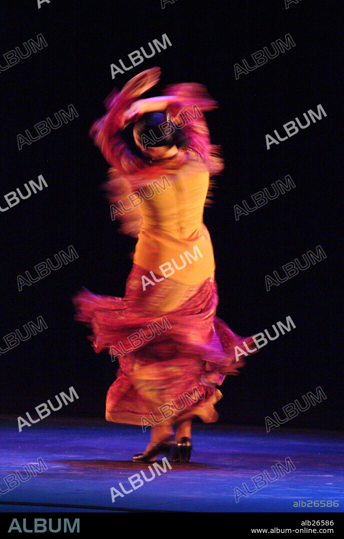 Mujer de espaldas bailando flamenco con un vestido naranja.