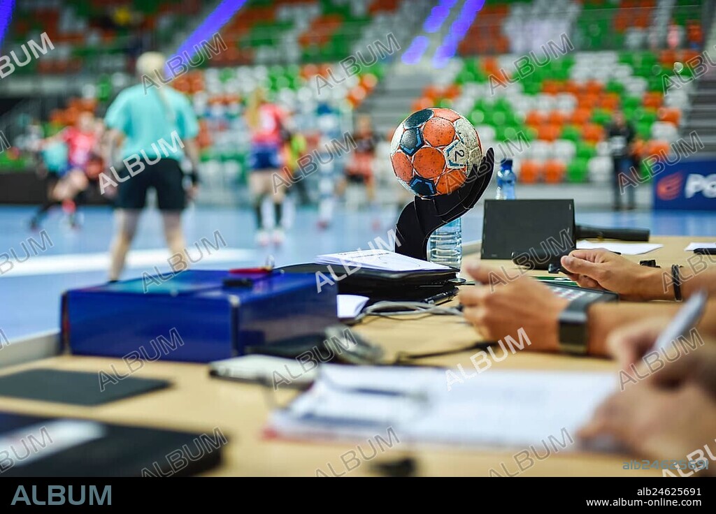 Ball on the referee's table and handball match in the background