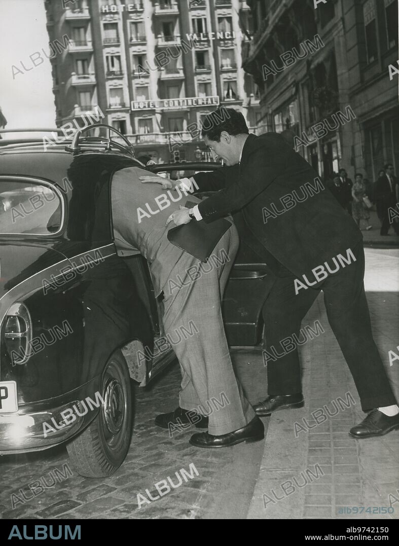 Madrid, mayo  de 1957. El periodista Manuel Menéndez Chacón ayuda al boxeador Primo Carnera a meterse en un taxi.
