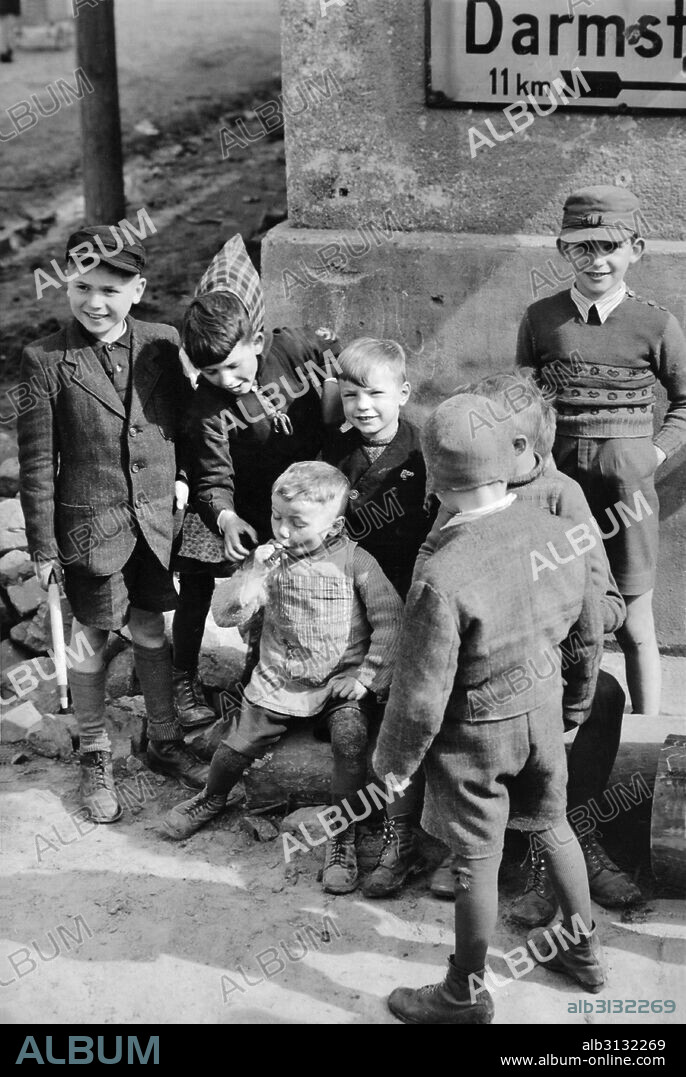 Buttelborn, Germany: April 4, 1945 While a group of youngsters looks on, a five-year-old German boy puffs on a cigar that was dropped by a soldier of the U.S. Third Army en route to Frankfurt.